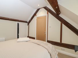 A bedroom with a bed a beige blanket wooden beams and a wooden door at The Old Haberdashery in Swanage
