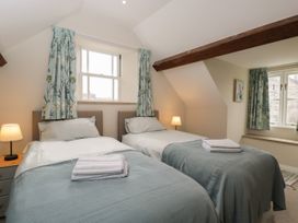 A bedroom with two single beds side by side and blue curtains at The Old Haberdashery in Swanage