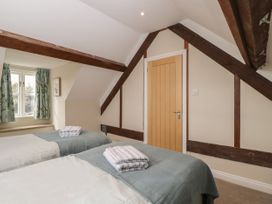 A bedroom with two beds folded towels on each bed wooden door and window with floral curtains at The Old Haberdashery in Swanage