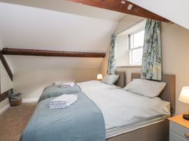 A bedroom with two single beds under a window with floral curtains and wooden beams at The Old Haberdashery in Swanage