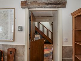 A hallway with a wooden door and staircase at Buzzards Breg in Builth Wells