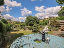A garden with a blue table and wine bottles at Buzzards Breg in Builth Wells