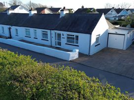 A row of white houses with black roofs and garages on a residential street at 3 Tai Newydd in Llanfaelog near Rhosneigr