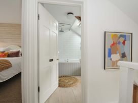 A bathroom with a bathtub visible through a door at Island House Golant near Tywardreath