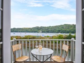 A balcony with chairs and a table overlooking a waterfront at Island House in Golant near Tywardreath