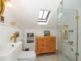 A bathroom with a shower and wooden dresser at Island House Golant near Tywardreath