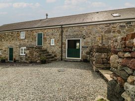 An outdoor area with a stone building and green door at No 1 The Granary Capel Coch near Llannerch-Y-Medd
