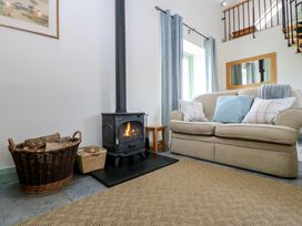 A living room with a sofa and a stove at No 1 The Granary in Capel Coch near Llannerch-Y-Medd
