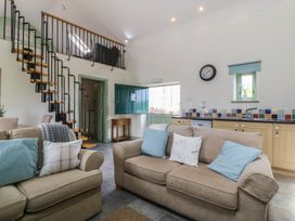 A living room with a sofa, armchair, and staircase at No 1 The Granary, Capel Coch near Llannerch-Y-Medd