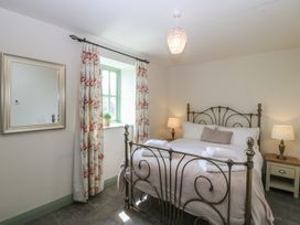 A bedroom with a bed, bedside tables, and windows at No 1 The Granary in Capel Coch near Llannerch-Y-Medd