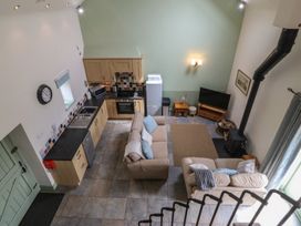 A living room with a sofa, TV, and kitchen area at No 1 The Granary, Capel Coch near Llannerch-Y-Medd