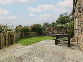 A garden with a stone wall and picnic table at No 1 The Granary Capel Coch near Llannerch-Y-Medd