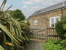 An entrance with a stone wall and wooden gate at No 1 The Granary in Capel Coch near Llannerch-Y-Medd