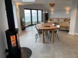 A living room with a stove, table, and sofa at The Old Coastguard Lookout in Port Isaac