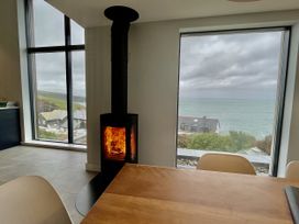 A dining room with a wood stove and large windows showing the coastline at The Old Coastguard Lookout Port Isaac