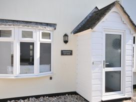 An exterior view of Shrimper's Cottage featuring a sign and windows in Tredrizzick near St Minver