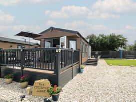A cabin with deck and gravel area at The Cotswold Holiday Lodge in Evesham