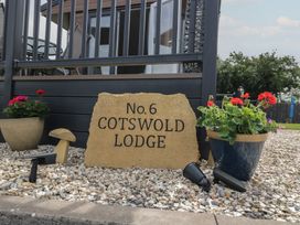 A sign stating No.6 Cotswold Lodge with flower pots in an outdoor area at The Cotswold Holiday Lodge Evesham