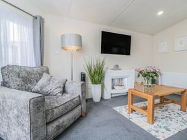 A living room with a sofa, television, and coffee table at The Cotswold Holiday Lodge in Evesham