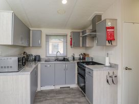 A kitchen with cabinets, sink, and appliances at The Cotswold Holiday Lodge in Evesham