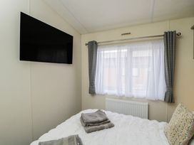 A bedroom with a TV, bed, and window at The Cotswold Holiday Lodge in Evesham