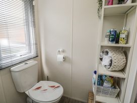 A bathroom with a toilet and shelves at The Cotswold Holiday Lodge in Evesham