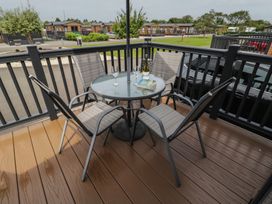 A table with chairs and drinks on a patio at The Cotswold Holiday Lodge in Evesham