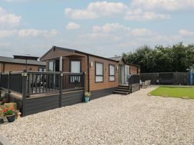 A mobile home with a deck and lawn at The Cotswold Holiday Lodge in Evesham