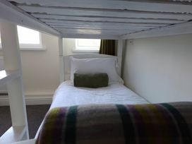 A bed with pillow and cushion under a loft bed at Teifi Villa in St Dogmaels