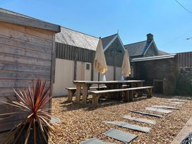 An outdoor area with a wooden table and umbrellas at Teifi Villa St Dogmaels