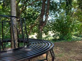 A bench under a tree in a garden at Teifi Villa, St Dogmaels