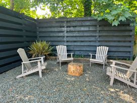 A garden area with chairs and a stump at Teifi Villa in St Dogmaels