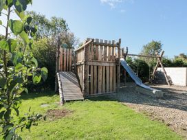 A playhouse with a slide and swing in the garden at Foxes Den in Allerston near Thornton Dale