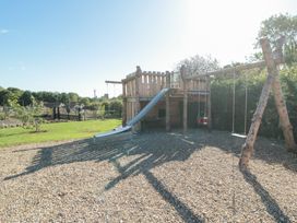 A playhouse with a slide and swings in an outdoor play area at Eagles Peak Allerton near Thornton-Le-Dale