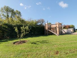 An outdoor playground with a wooden playhouse and tree at Eagles Peak, Allerton near Thornton-Le-Dale