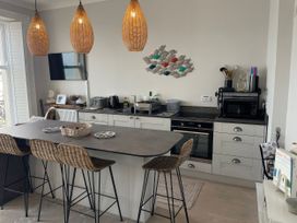 A kitchen with a large island and bar stools at Sunrise Apartment in Weymouth