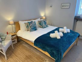 A bedroom with a double bed, lamps, and a chair at Sunrise Apartment in Weymouth