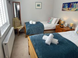 A bedroom with two beds and a bedside table at Sunrise Apartment in Weymouth
