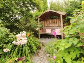 A garden with a wooden seat surrounded by plants and flowers at West View in Leasgill near Milnthorpe