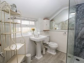 A bathroom with a sink, toilet, shower, and shelf at Bay Tree Cottage in Ambleside
