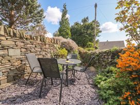 A garden with a stone wall, table, and chairs at Bay Tree Cottage in Ambleside