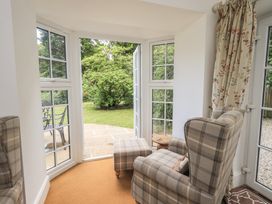 A conservatory with armchairs and garden view at The Old Post House at Low Stott Park near Newby Bridge