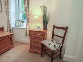 A room with a table lamp and a chair beside a window at The Old Post House at Low Stott Park