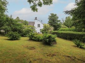 A garden with a house and trees at The Old Post House at Low Stott Park near Newby Bridge