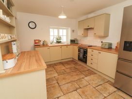 A kitchen with countertops, appliances and a clock at The Old Post House at Low Stott Park near Newby Bridge
