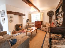 A living room with a fireplace two armchairs a sofa a wooden coffee table a chest of drawers and a large clock at The Cottage in Halkyn near Holywell
