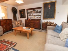 A living room with armchairs a sofa a wooden coffee table a chest of drawers and a cabinet with plates and decorative items at The Cottage in Halkyn near Holywell