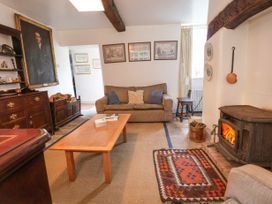 A living room with a sofa coffee table wood burning stove and framed pictures at The Cottage in Halkyn near Holywell