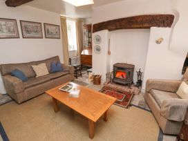 A living room with a wood stove fireplace two sofas a wooden coffee table and framed pictures on the wall at The Cottage in Halkyn near Holywell