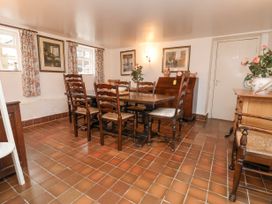 A dining room with wooden chairs around a table and floral curtains at The Cottage in Halkyn near Holywell